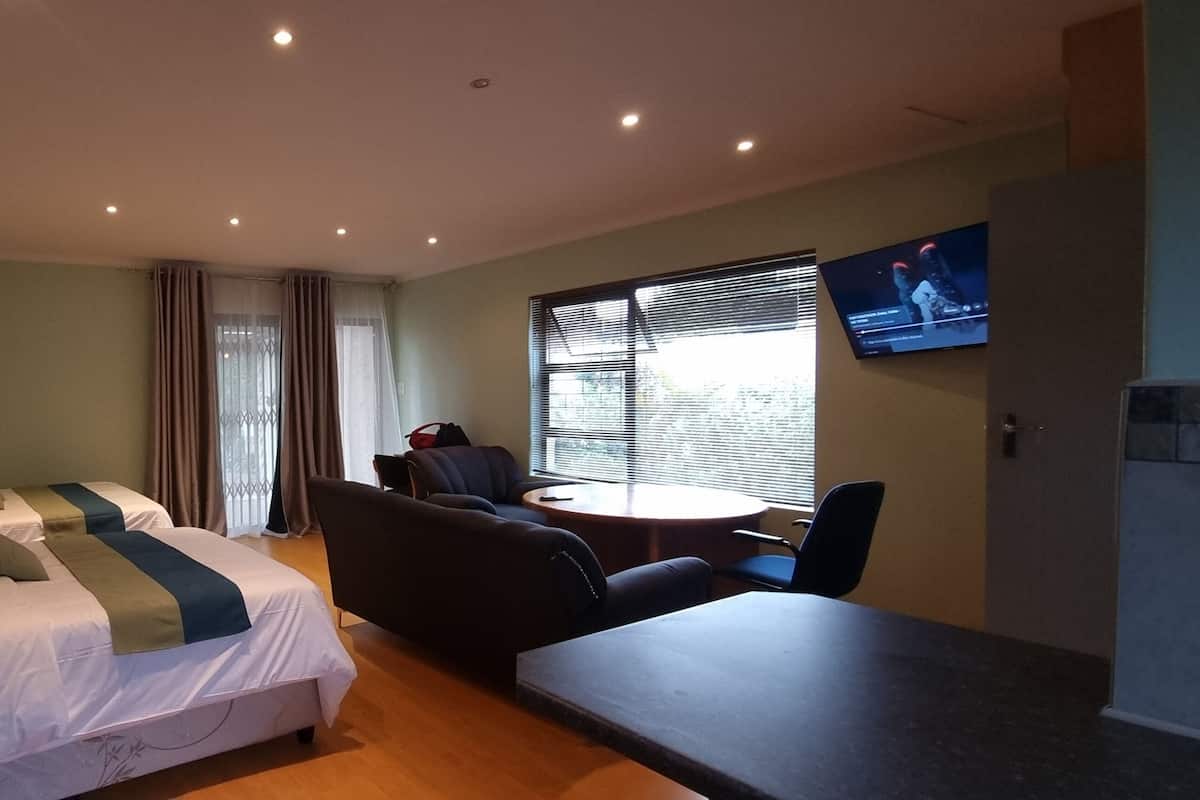 Una camera d'albergo con un letto, un divano, un tavolino, una televisione e una finestra con tende.