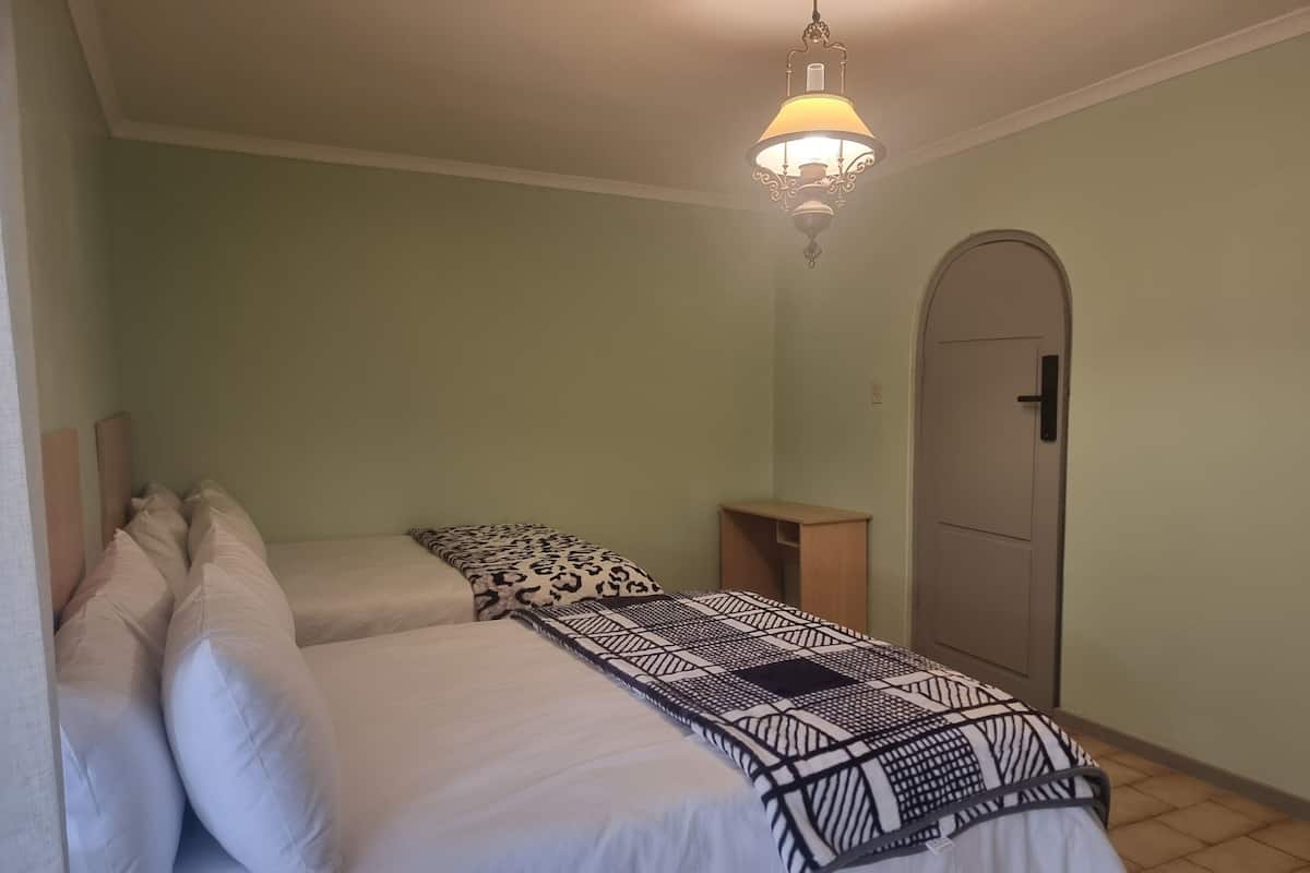 Una camera da letto con due letti, un comodino, un armadio e una lampada a sospensione.
