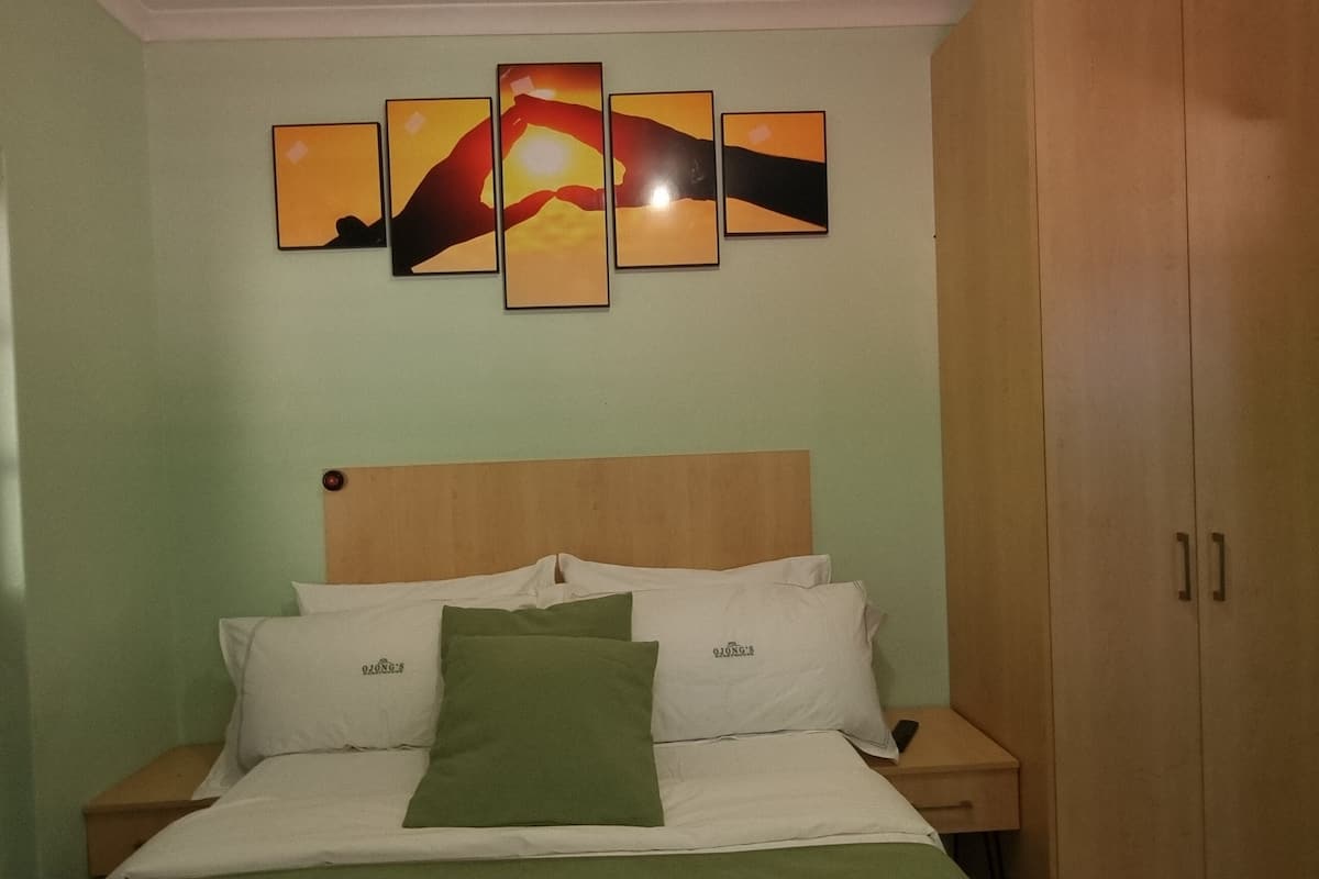 Una camera da letto con un letto, comodini, un armadio in legno e una parete con arte astratta.
