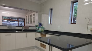 A kitchen with white cabinets, a black countertop, and a window with a view of trees.