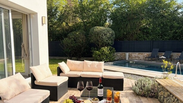 Un espace extérieur aménagé avec des sièges, une piscine, des meubles en osier et une planche de charcuterie.