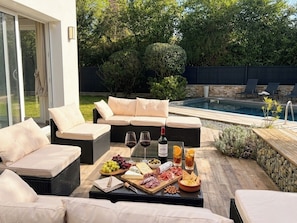 An outdoor seating area with a pool, wicker furniture, and a charcuterie board.