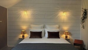Une chambre à coucher avec un grand lit, deux lampes de chevet et un luminaire fixé au mur.
