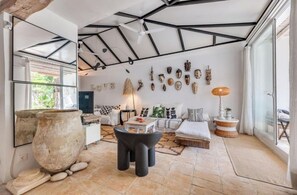 A modern interior with a high ceiling, a large stone pot, a sofa set, and a wall adorned with various masks. - Magnificent 3-bedroom Andalusian family villa near the beach and Puerto Banús (Marbella)