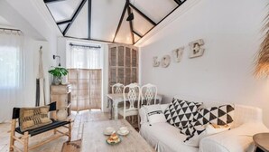A cozy living room with a white sofa, a wooden coffee table, and a dining area with white chairs and a wooden table. - Magnificent 3-bedroom Andalusian family villa near the beach and Puerto Banús (Marbella)