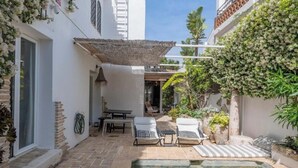 A courtyard with a pool, lounge chairs, and potted plants. - Magnificent 3-bedroom Andalusian family villa near the beach and Puerto Banús (Marbella)