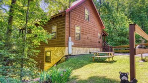 A rustic wooden cabin with a porch, surrounded by lush greenery. - Mountain Views & Hot Tub | Near Dollywood (Sevierville)