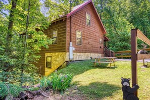 A rustic wooden cabin with a porch, surrounded by lush greenery. - Mountain Views & Hot Tub | Near Dollywood (Sevierville)