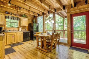 A wooden cabin with a kitchen, dining area, and large windows. - Bear-rif-ic Cabin w/ Hot Tub & Pool Table (Sevierville)