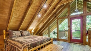 A wooden interior with a bed, bench, and large windows. - Mountain Views & Hot Tub | Near Dollywood (Sevierville)