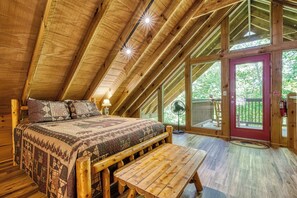 A wooden interior with a bed, bench, and large windows. - Mountain Views & Hot Tub | Near Dollywood (Sevierville)
