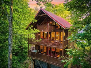 A multi-story wooden cabin with balconies, surrounded by dense forest. - Bear-rif-ic Cabin w/ Hot Tub & Pool Table (Sevierville)