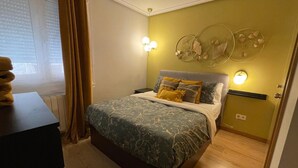 Een slaapkamer met een bed, nachtkastjes, een raam met gordijnen en wanddecoratie.