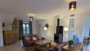 A living room with a fireplace, leather sofas, a wooden coffee table, and a bar area with stools.