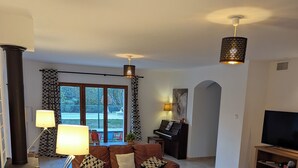 A living room with a sofa, coffee table, TV, and piano.