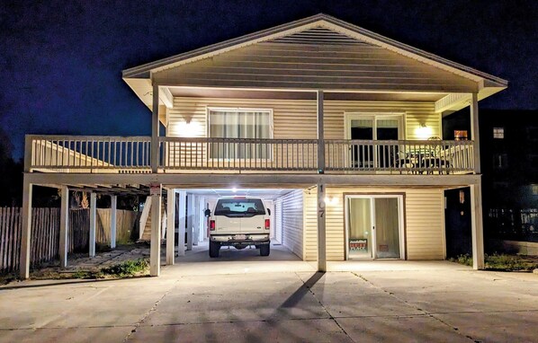 Une maison à deux étages avec un garage, une véranda et un balcon.