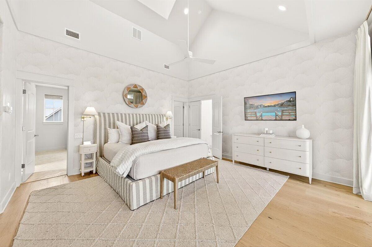 Un dormitorio con cama, mesitas de noche, un banco, cómoda y un cuadro en la pared.