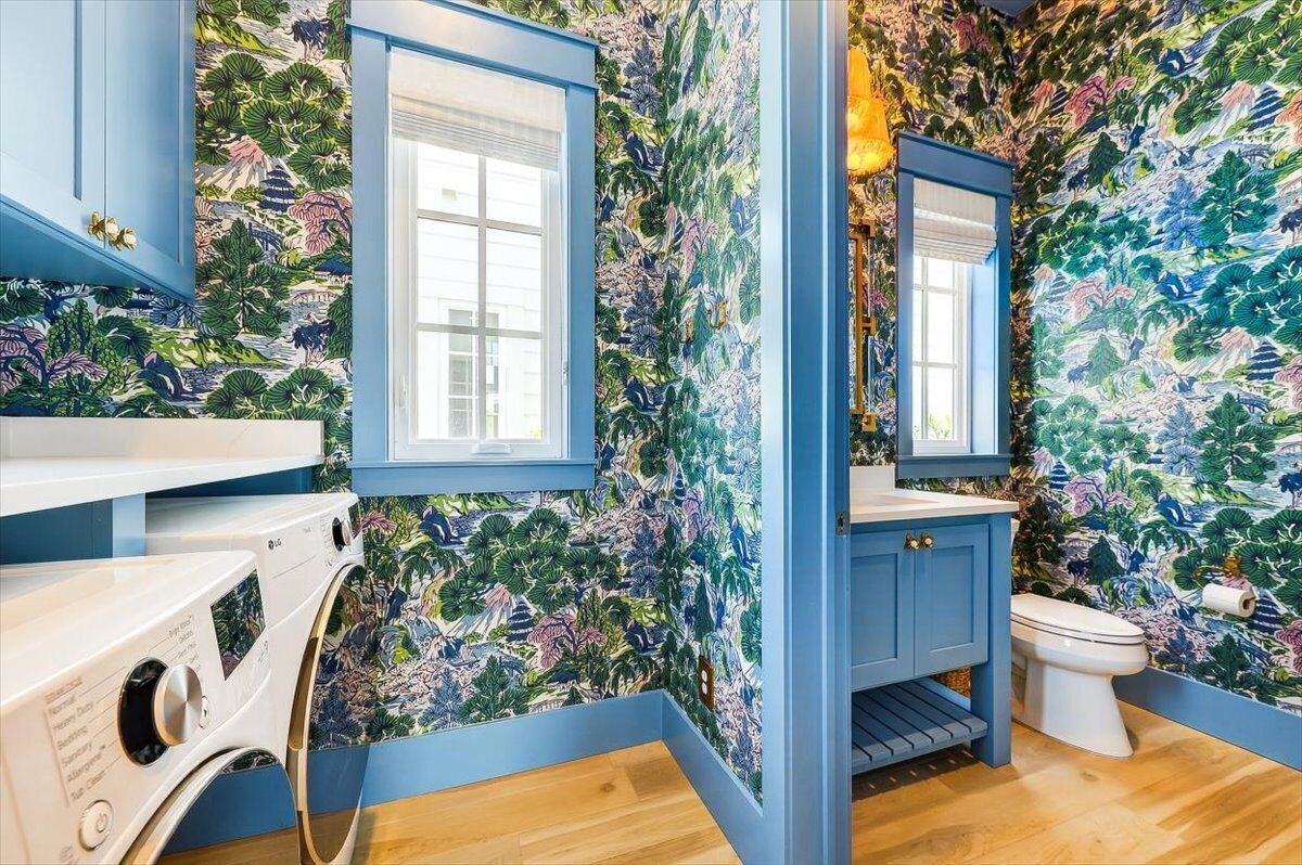 A bathroom with a blue theme, a washing machine, and a toilet.