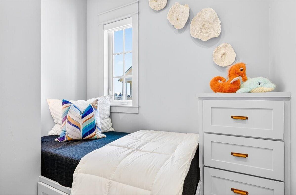 Un dormitorio con cama, cómoda, ventana y conchas decorativas en la pared.