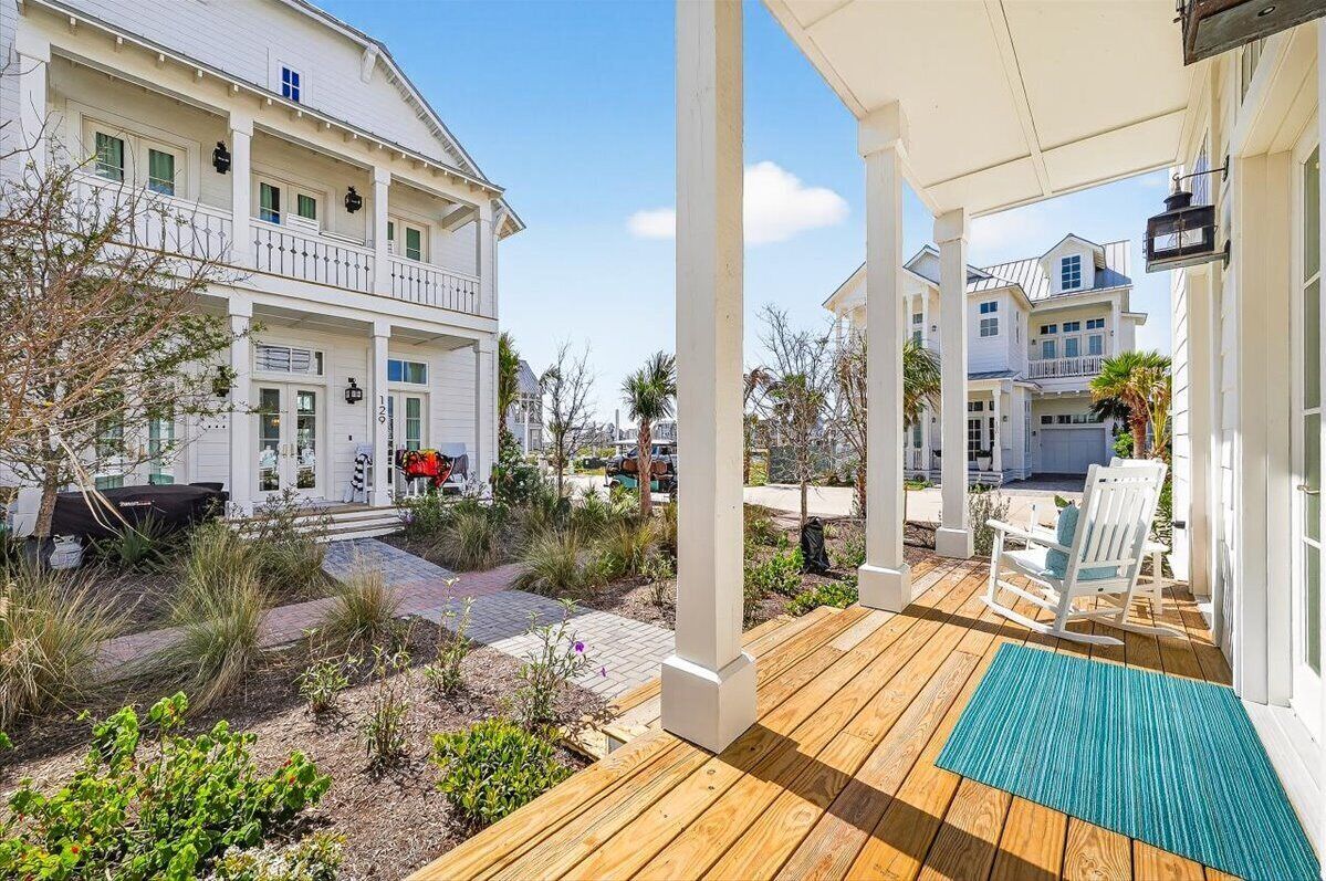 A coastal house with a wooden deck, a covered porch, and a view of neighboring houses.