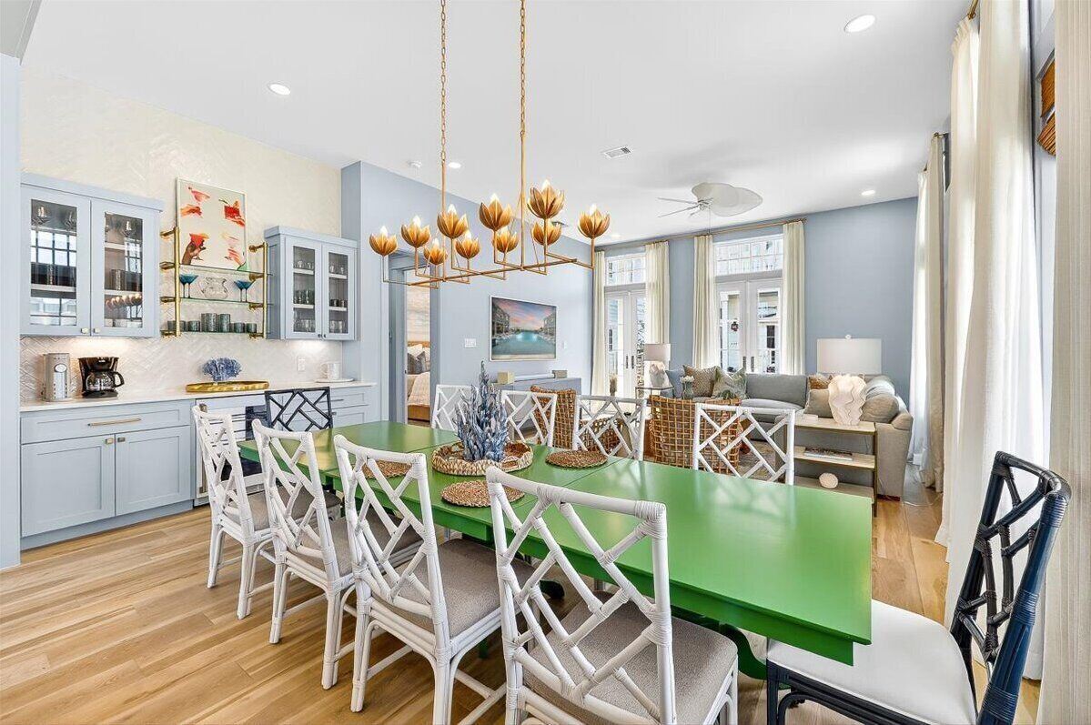 A modern kitchen with white cabinets, a green dining table, and wicker chairs.