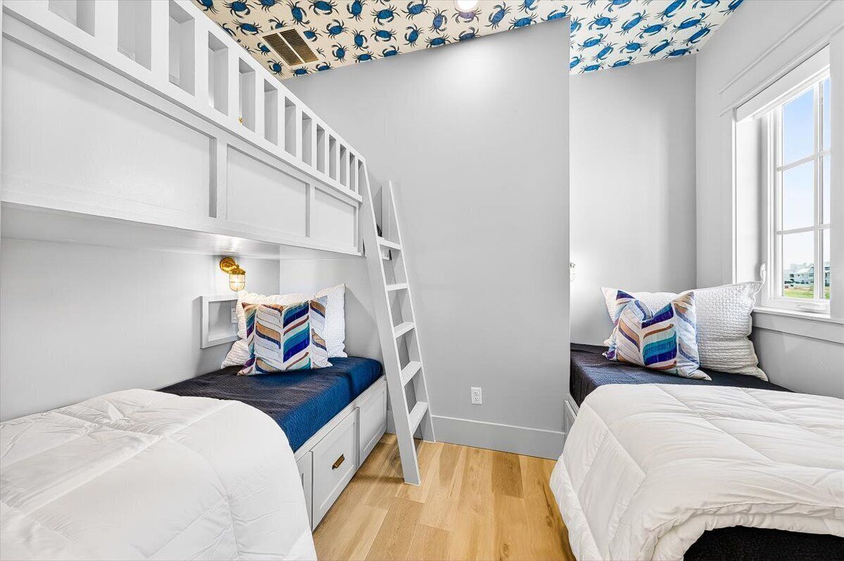 A bedroom with two beds, a ladder, and a window.