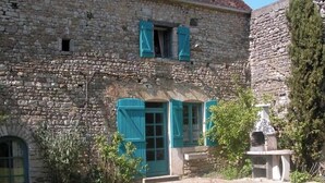Un bâtiment en pierre doté d’un jardin, d’une statue et d’une petite fontaine.