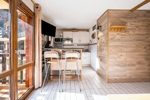 Eine moderne Küche mit Essbereich, Holzakzenten und Blick durch ein großes Fenster.