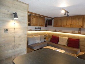 Ein gemütliches Zimmer mit Holzwand, einer Couch mit Kissen, einem Tisch und Holzschränken.
