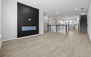 A spacious living area with a fireplace, a staircase, and a kitchen in the background. - Spacious 3-bedroom house with office in beautiful Dallas for the World Cup (Dallas)
