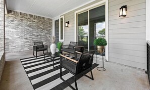 A covered patio with a black and white striped rug, a table with chairs, a potted plant, and a brick wall. - Spacious 3-bedroom house with office in beautiful Dallas for the World Cup (Dallas)
