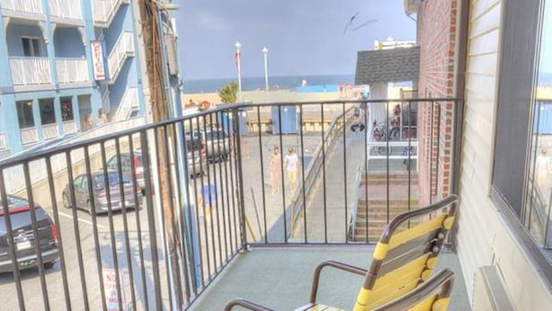 Un balcon avec une chaise, une vue sur la rue et un immeuble doté de balcons.
