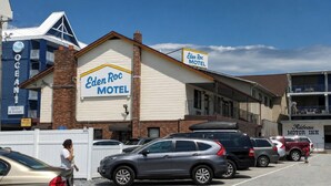 Un motel avec une enseigne bien visible, un parking où sont garées plusieurs voitures et un bâtiment portant l’inscription « Eden Roc Motel ».