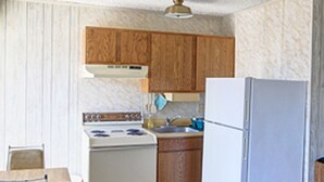 Une cuisine de taille réduite, avec des meubles de rangement en bois, une cuisinière blanche et un réfrigérateur.