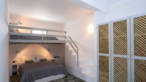 Camera con letto a castello, una piccola scrivania e un armadio con decorazioni a griglia.