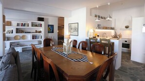 Un soggiorno moderno con zona pranzo, cucina e libreria piena di libri e oggetti decorativi.