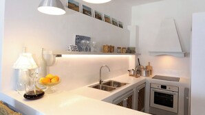 Una cucina moderna con un lavello doppio, elettrodomestici in acciaio inossidabile e un piano di lavoro bianco.