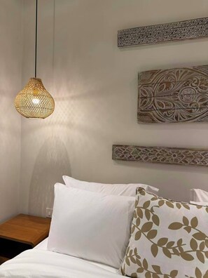 A bedroom with a bed, white pillows, a woven pendant light, and decorative wall art. - Your Private Design Oasis in Canggu Bali Villa No. 1 (mengwi)