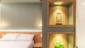 A modern bedroom with a bed, a wall-mounted plant, and a framed picture of an hourglass.