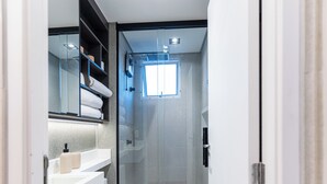 A modern bathroom with a glass shower enclosure, a white sink, and a towel rack.
