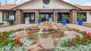 A building with a stone facade, a sign reading 'Asteria,' and a landscaped area with a small waterfall and flowers. - The Asteria by Stylish Stays (Tempe)