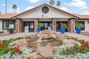 A building with a stone facade, a sign reading 'Asteria,' and a landscaped area with a small waterfall and flowers. - The Asteria by Stylish Stays (Tempe)