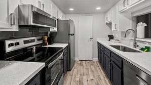 A modern kitchen with stainless steel appliances, white cabinetry, and a wooden floor. - The Asteria by Stylish Stays (Tempe)