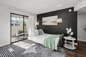 Een moderne slaapkamer met een bed, een nachtkastje, een lamp en een schilderij aan de muur.