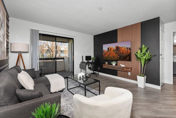 A modern living room with a sofa, armchair, coffee table, and a large painting on the wall. - The Asteria by Stylish Stays (Tempe)