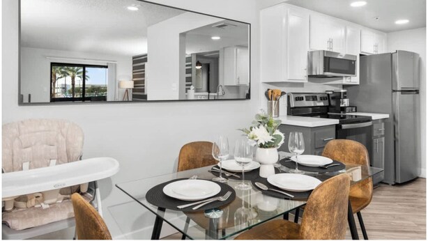 A modern dining area with a glass table, chairs, and a view of the kitchen. - The Asteria by Stylish Stays (Tempe)
