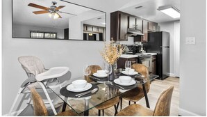 A modern dining area with a glass table, chairs, and a ceiling fan. - The Asteria by Stylish Stays (Tempe)