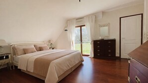 A bedroom with a bed, dresser, nightstand, lamp, and a view of the outdoors. - Maison Familiale- Carnac & La Trinité (Carnac)