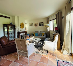 A living room with a sofa, armchairs, a coffee table, a fireplace, and a window with curtains. - Maison Familiale- Carnac & La Trinité (Carnac)