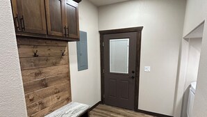 A hallway with wooden flooring, a bench, a door with a window, and wooden cabinets. - Gorgeous rustic modern home tucked away in Texarkana - 4 bedrooms available (Texarkana)